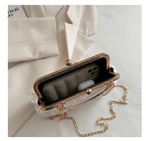Detail showing the internal capacity of the white lace clutch with a golden chain strap