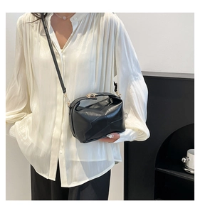 Détail du sac seau noir en cuir avec une élégante boucle en métal doré et texture