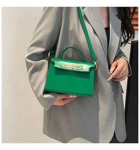 Detalle de un mini bolso de cuero verde lima con cierre dorado sobre una chaqueta gris