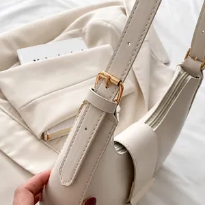 Detail of adjustable metal buckle on beige leather shoulder bag strap with gold hardware