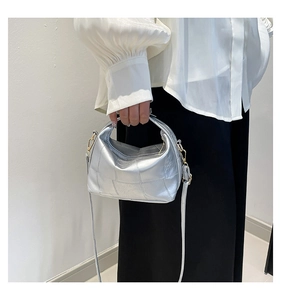 Détail d'un sac seau tressé argenté avec ferrures dorées et bandoulière amovible