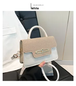 Detail of white crossbody bag with textured flap and gold metal buckle on a neutral backdrop