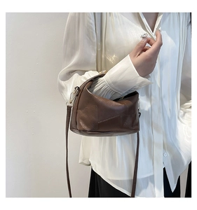 Détail du sac seau patchwork marron foncé avec bandoulière amovible porté par un modèle