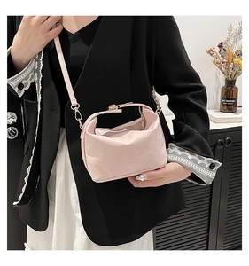 Sac seau rose avec motif en cuir quadrillé et détails dorés sur un mannequin femme