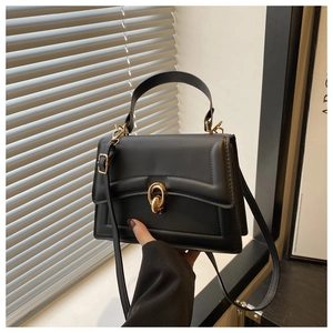 Dettaglio di una borsa a tracolla nera strutturata con fibbia dorata intrecciata chic