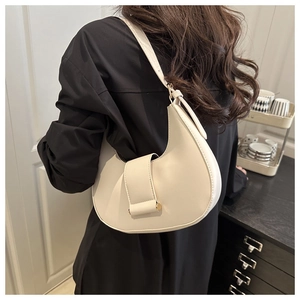 Detail of cream crescent shoulder bag with gold sphere hardware on a model