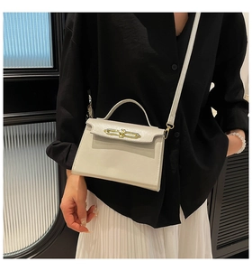 Detalle de bolso de cuero crema con cierre dorado en modelo con camisa negra