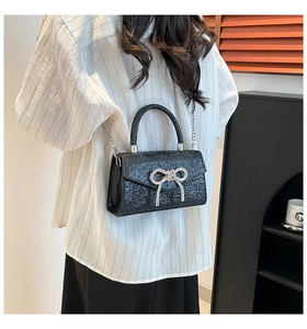 Detail of glittery mini crossbody bag with silver rhinestone bow and metal handle