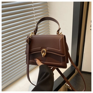 Dettaglio della borsa a tracolla in pelle marrone scuro con elegante fibbia dorata
