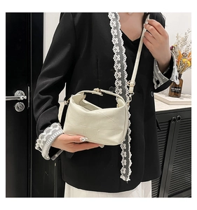 Détail du sac seau crème avec surpiqûres carrées et boucles dorées porté par un modèle