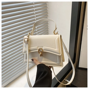 Dettaglio di una borsa bianca minimalista con chiusura a scatto dorata e manico superiore