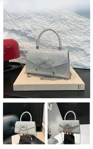 Detail of silver sequin evening bag with a rhinestone bow and sleek metallic chain