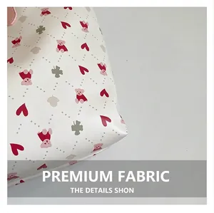 Détail du tissu blanc de sac cabas avec motifs d'ours, cœurs et trèfles en disposition