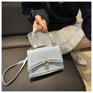 Dettaglio della mini borsa a mano azzurra con fibbia dorata, indossata dalla modella
