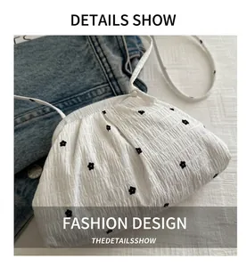 Détail du sac nuage à volants blancs avec imprimé floral noir sur fond de veste en jean
