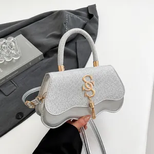 Silberne Pailletten-Handtasche mit Wellenboden und goldenem S-Logo mit Fransen-Quaste