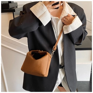 Détail de la texture tissée marron sur le sac bandoulière avec boucle dorée