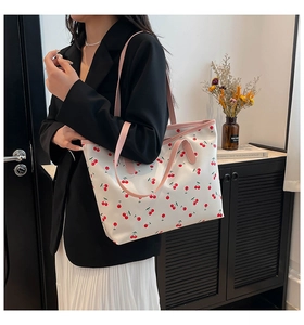 Détail d'un grand sac cabas à imprimé cerise avec des anses en cuir rose sur un modèle