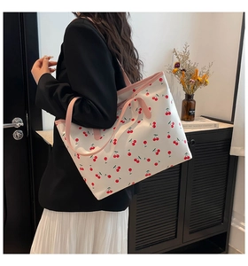 Détail d'un sac cabas blanc avec motifs cerises rouges et bandoulières roses