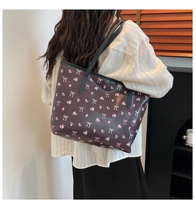 Détail du sac cabas marron foncé avec motifs floraux roses et nœuds porté à l'épaule