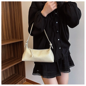 Detail of a creamy white baguette bag featuring pleated texture and silver buckle hardware