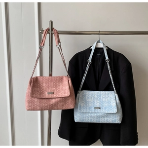 Close-up of woven texture flap shoulder bags in pink and blue with metal chain straps