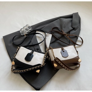 Detail view of stylish color-block bucket bags with gold metal corners and chain straps