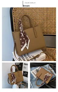 Detailansicht der braunen Ledertasche mit herzgemustertem Seidenschal am Handgriff