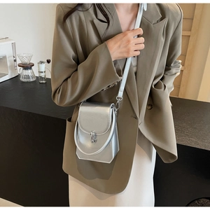 Détail du mini sac bandoulière argenté avec boucle métallique sur un comptoir