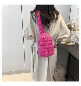 Close-up of quilted nylon crossbody bag in hot pink finish worn with a beige trench coat