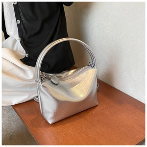 Detail of silver metallic handbag with pleated texture and round zipper charm