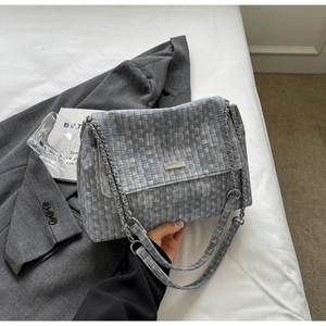 Detail of light blue woven tote bag with silver chain strap and metal buckle decor
