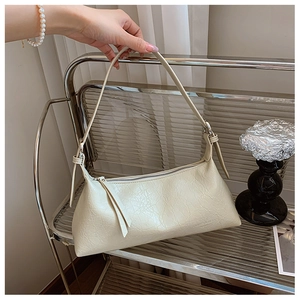 Macro view of cream baguette bag showing refined leather texture and zipper detail