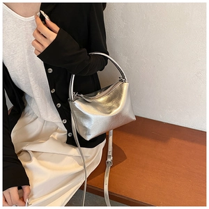 Silver metallic pleated handbag worn crossbody with black cardigan and beige pants