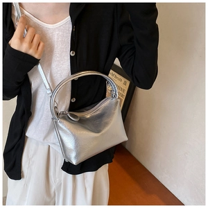 Detail of silver metallic crossbody bag showing glossy texture and detachable strap