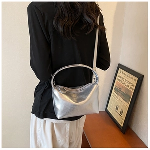 Detail of silver metallic handbag with smooth texture, ring handle and slim shoulder strap