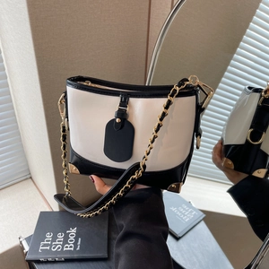 Contrast color bucket bag with black and white leather, chain strap, and golden corners