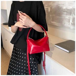 Close-up of a stylish red semi-circular handbag held by a model in a modern indoor setting