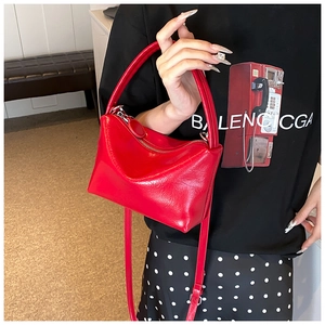 Detail of red glossy wrinkled texture PU leather handbag with metallic zipper and strap