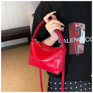 Detailed view of glossy red synthetic leather handbag with silver zipper and carry handle