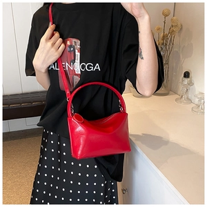 Detail of red glossy leather handbag with curved handle on a minimalist background
