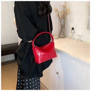 Detail of a red glossy minimalist crossbody handbag with a sleek metallic zipper closure
