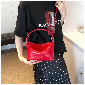 Close-up of a bright red glossy leather handbag with silver hardware and shoulder strap