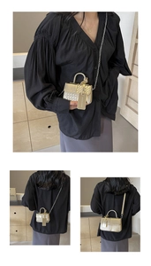 Detail of a mini gold crossbody bag featuring woven texture and metallic handle on model