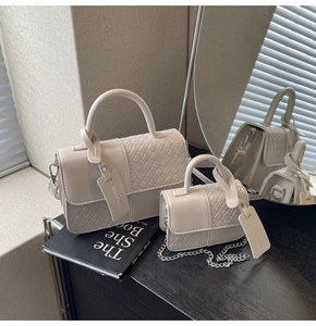 Detail of cream woven and smooth textured handbags with elegant silver chain straps