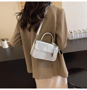 Silver woven textured crossbody bag styled with a brown blazer in a warm indoor setting