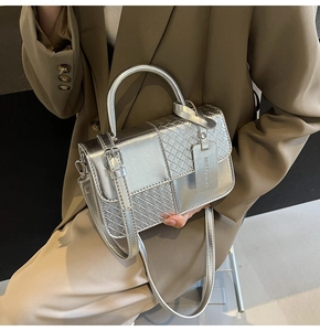 Detail of silver woven texture on leather handbag with adjustable strap and fashion tag