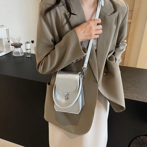 Petit sac à bandoulière argenté métallisé pour femme porté dans un café urbain chic