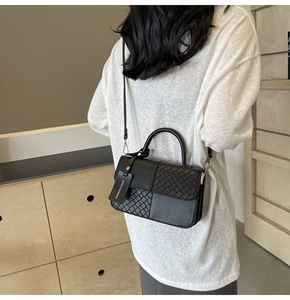 Detail of black woven texture leather bag with silver hardware and fashion hanging tag