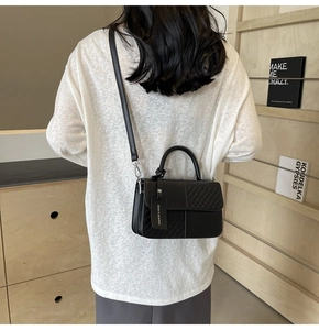 Detail of black minimalist handbag with woven and smooth texture combination